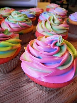 A table topped with Quinceanera cupcakes covered in rainbow frosting