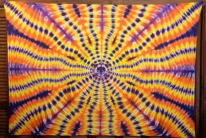 A colorful tie dye pillow on a wooden table, pattern perfect for a Quinceanera celebration.