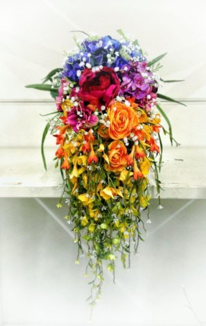 A colorful floral design featuring a rainbow bouquet of flowers hanging from a wall, perfect for a Quinceanera celebration