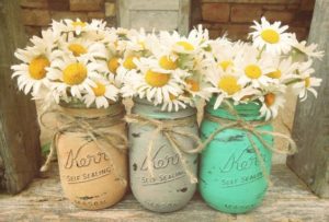 Quinceanera, three mason jars with daisies in them sitting on a bench, rustic bridal shower idea