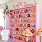 A Quinceanera-themed doughnut wall featuring a display of donuts on a pink wall