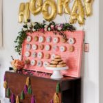 A Quinceanera-themed table with a display of donuts covered in gold balloons