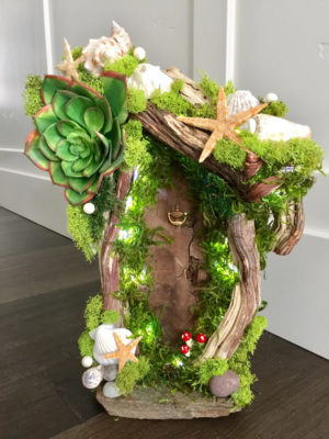 A whimsical Quinceanera woodland theme featuring a small fairy house made of wood and moss