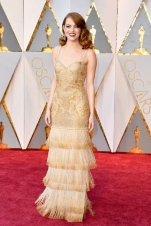 Emma Stone, a woman in a gold dress on a red carpet at a Quinceanera event