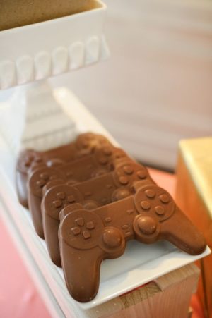 A Quinceanera-themed image featuring a chocolate bar shaped like a video game controller.