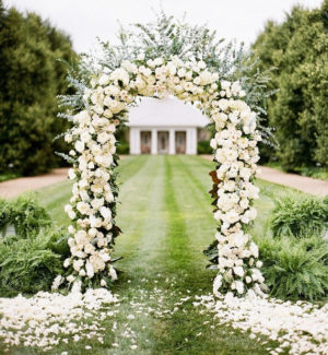 A Quinceanera arch decorated with white flowers and greenery