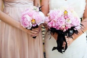 Two bridesmaids at a Quinceanera hold bouquets of pink and white flowers