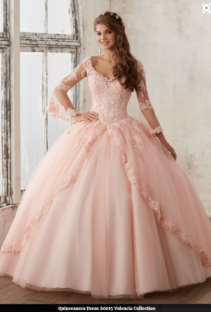 A woman in a pink ball gown posing for a picture at a Quinceañera event