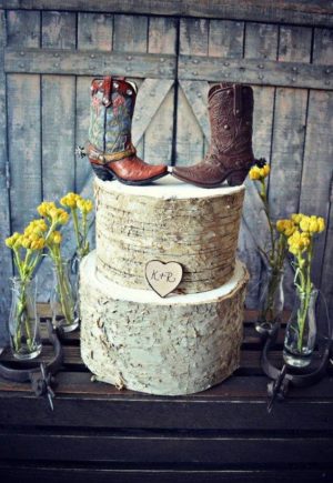 A Quinceanera themed cake with cowboy boots on top of a three-tiered cake