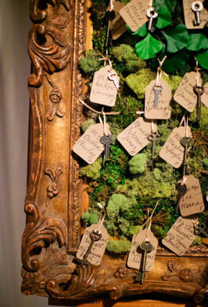 A picture of a moss-covered frame with tags attached to it, representing a Quinceanera theme.