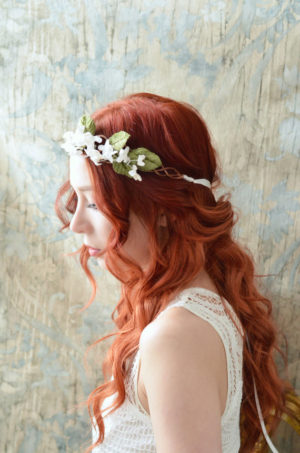 A woman with red hair wearing a Quinceanera headpiece and a flower crown