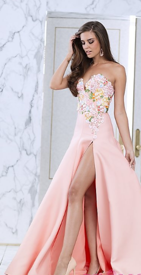 Quinceanera fashion model wearing a pink gown standing in front of a door