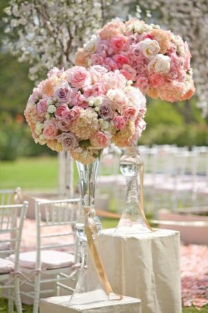 A Quinceanera-themed table featuring a reversible trumpet vase filled with pink and white flowers