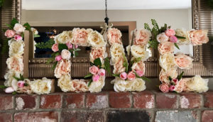 Floral design of a quinceanera flower bouquet with the word love made of flowers on a brick wall