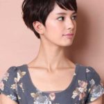 A woman with short hair and bangs wearing a floral shirt