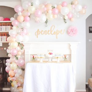A table with a Quinceanera cake and balloons on it, surrounded by eighteen pies balloons