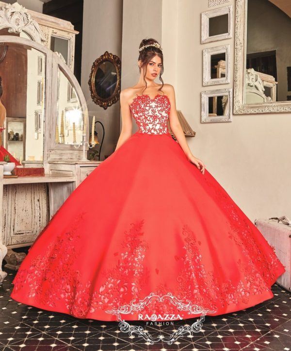 A woman wearing a red Quinceañera gown standing in front of a mirror