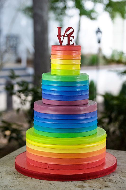 A multicolored Quinceanera cake with a love sign on top