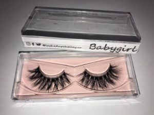 A clear box containing false eyelashes and a tube of eyelash mascara for a Quinceanera beauty look.
