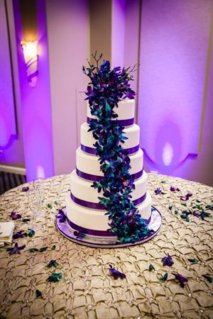 Quinceanera cake and invitation, a white cake with purple and teal decorations