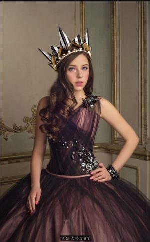A woman in a Quinceanera gown and crown poses for a picture