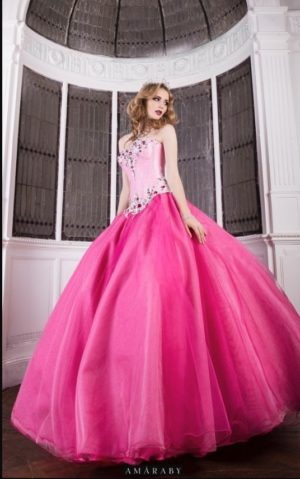 A woman in a pink Quinceañera gown standing in a room
