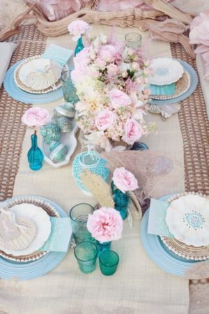 Quinceanera table set with plates, vases, and flowers in a pastel motif