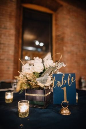 A navy blue and gold combination - A table with candles and a Quinceanera table number
