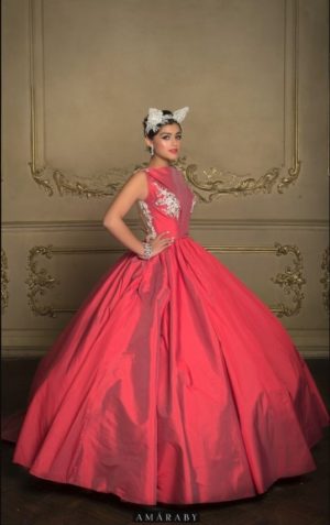Woman in a red dress posing for a picture wearing a Quinceañera gown