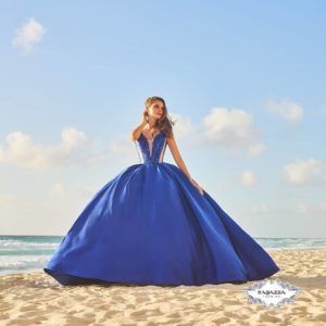 Quinceanera gown, a woman in a blue dress sitting on a beach