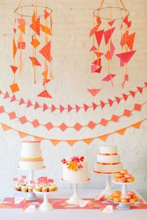 A Quinceanera themed table with orange decorations. The table features a cake and cupcakes.