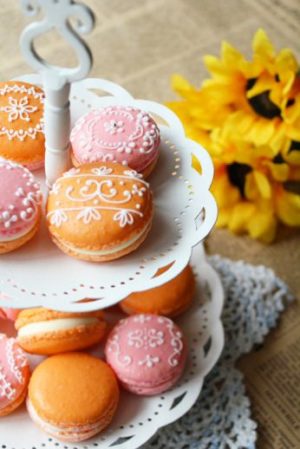 Macaroon, a three tiered cake plate with a bunch of donuts on it