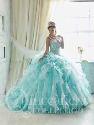 A woman in a ball gown standing in front of a window. The colors of the dress remind of a summer quinceanera.