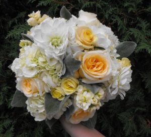 A person holding a bouquet of white and yellow flowers in a floral design for a Quinceanera celebration