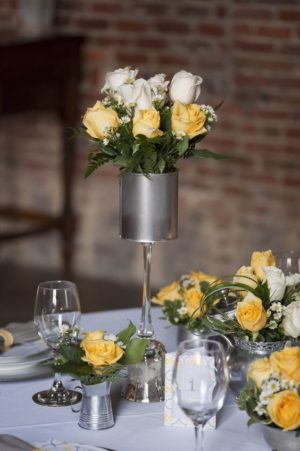 A Quinceanera centrepiece, featuring a table set with a vase of yellow and white roses