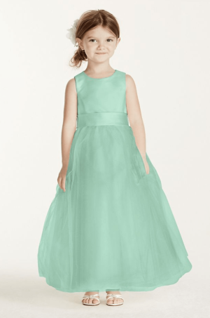 Quinceanera image: A group of people at a Quinceanera celebration. The bridal party is dressed in matching outfits. A little girl in a green flower girl dress stands amongst them.