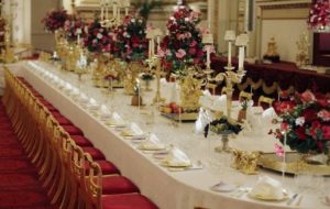 A festive Quinceanera table set with a long red table and chairs decorated with a royal theme