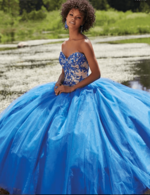 A woman in a blue dress sitting on a rock, wearing a beautiful quinceanera gown
