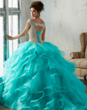 A woman in a aqua Quinceañera dress, standing in front of a window