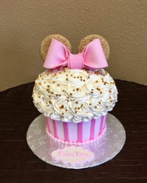 A Quinceanera cupcake with buttercream Chantilly cream, decorated with white frosting and a pink bow