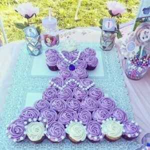 A Quinceanera themed image featuring a cupcake shaped like a dress on a table, inspired by Princess Sofia's birthday.