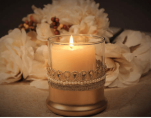 A lit Unity candle sitting on top of a table next to flowers, representing a Quinceanera celebration.