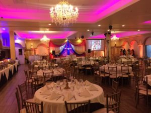 Quinceanera reception in a grand function hall decorated with tables and chairs, complete with a beautiful chandelier