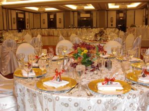 A table set for a Quinceanera event in a function hall called Royal Banquet. The table is elegantly decorated with white and gold decorations.