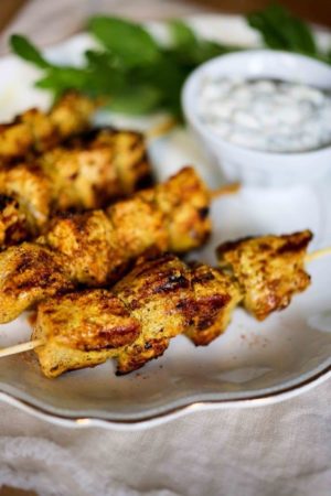 Quinceanera image: A white plate topped with chicken skewers next to a bowl of dip