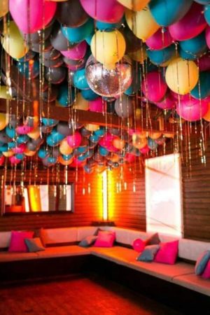 A Quinceanera party theme inspired by the 80s 1980s, showcasing a room filled with lots of balloons hanging from the ceiling.