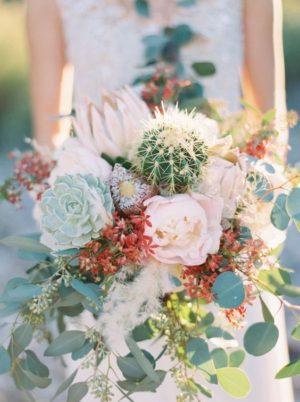 A Quinceanera celebration, a woman in a Quinceanera dress holding a bouquet of flowers in the desert