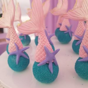 Cake decorating for a Quinceanera, featuring a white plate topped with blue and pink cupcakes
