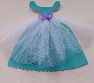 A turquoise Quinceañera paper doll wearing a blue dress and a purple bow.