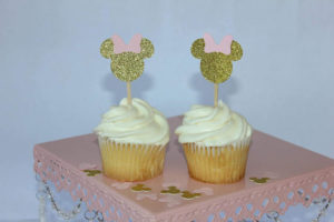 Two buttercream cupcakes on a pink cake stand at a Quinceanera celebration.